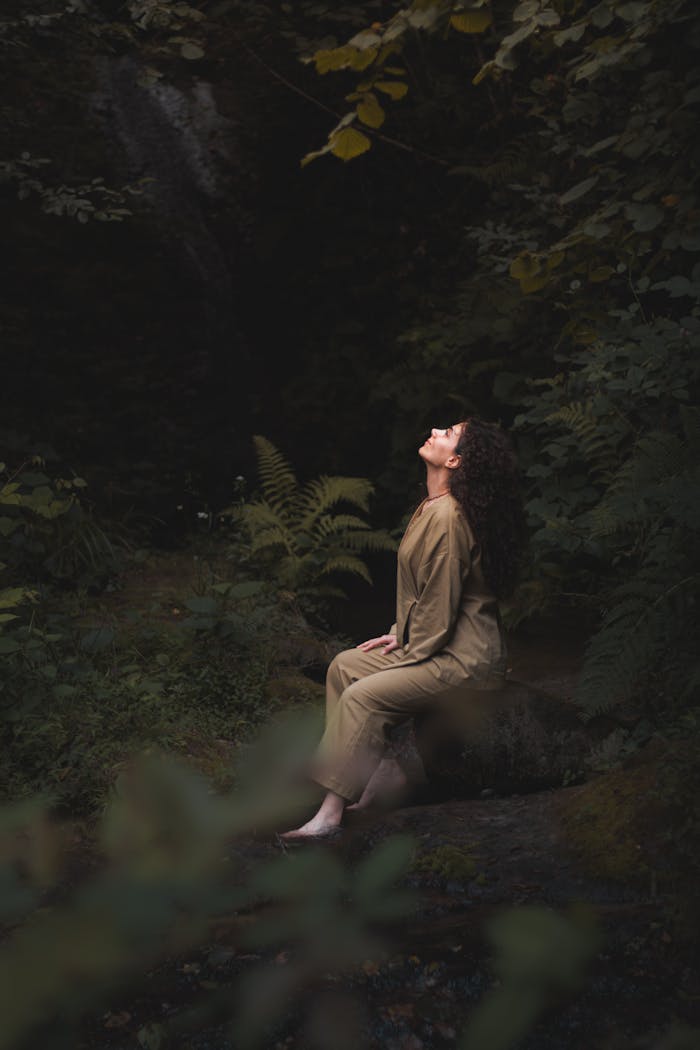 Young woman meditating in a tranquil forest setting, embracing nature's serenity.