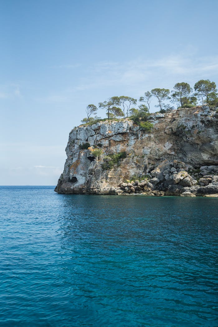 Stunning view of a rocky cliff over turquoise waters in Mallorca, Spain, showcasing natural beauty.