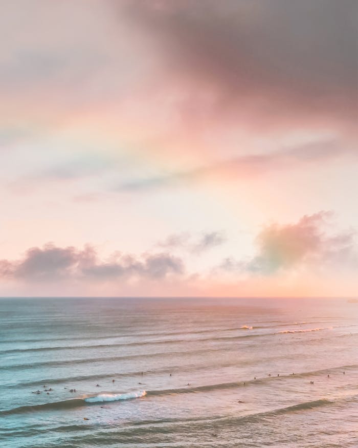 Dramatic Hawaiian sunset over the ocean with gentle waves and a vivid sky.