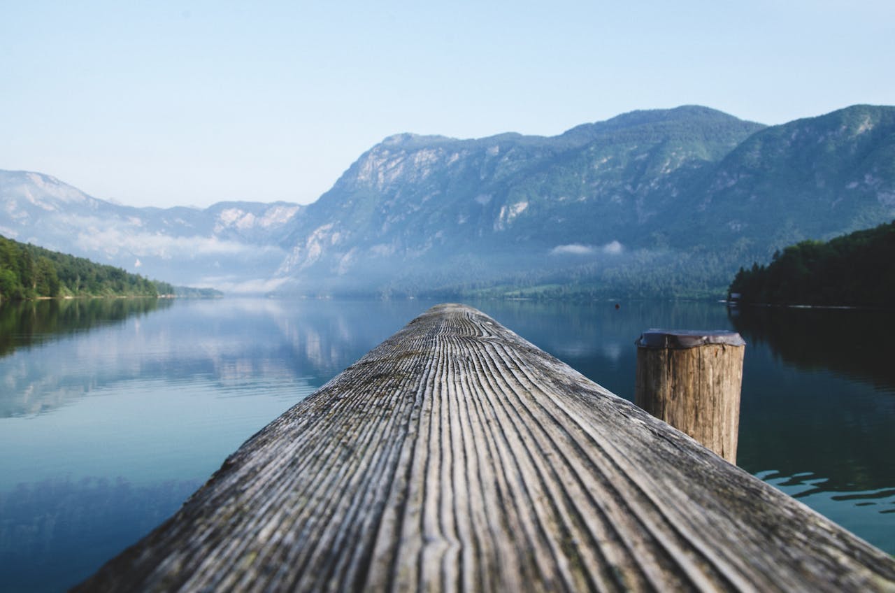 services-02 Serene view of a mountain lake from a wooden dock in Radovljica, Slovenia.