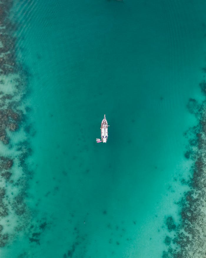 Stunning aerial shot of a boat floating in the clear blue waters of Thailand's coast.