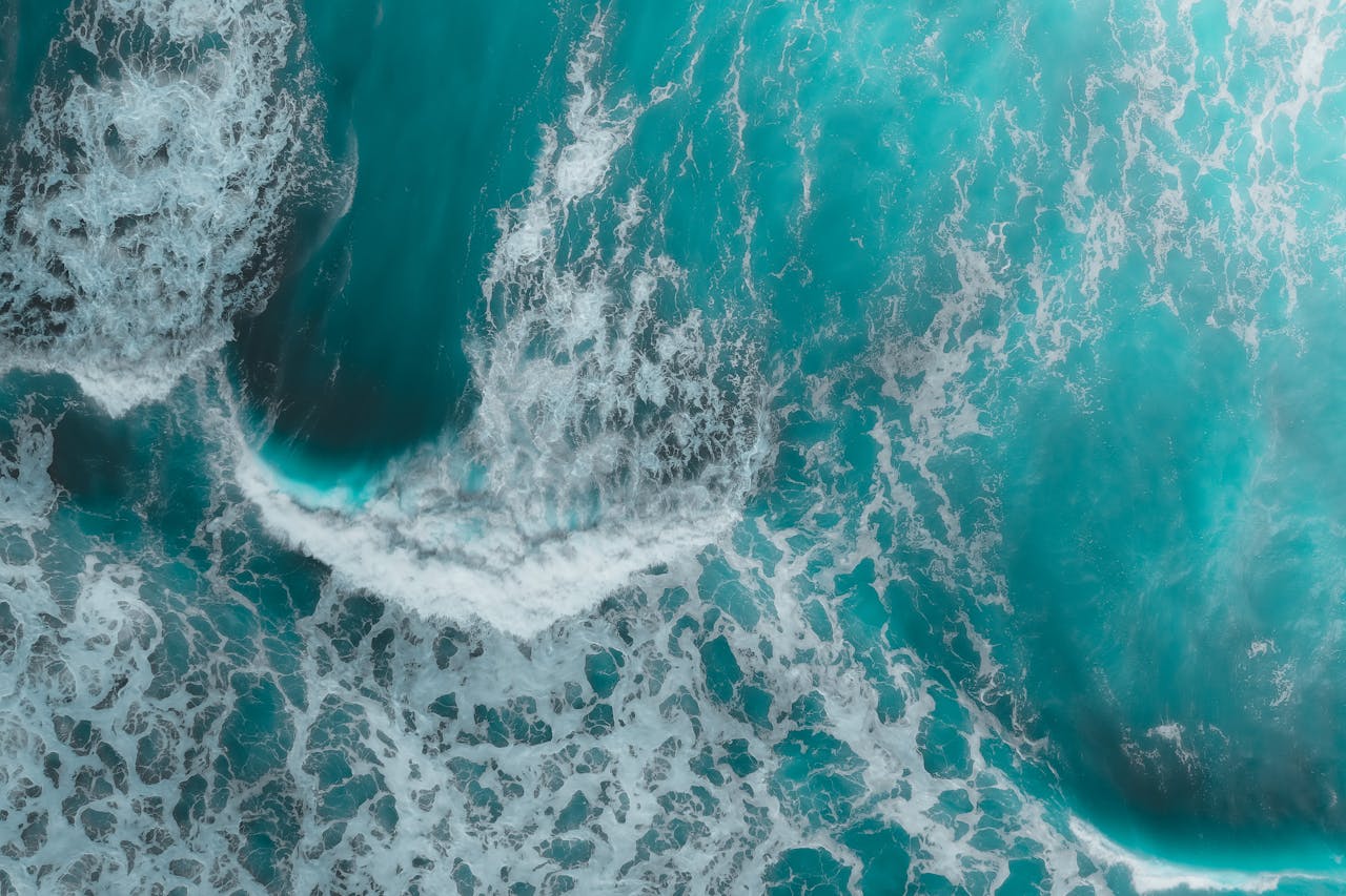 A stunning aerial view of turquoise ocean waves crashing, creating a mesmerizing texture.